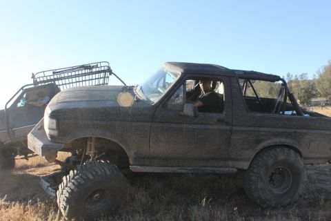1992 Ford Bronco side view, mud-covered with roll cage and roof rack