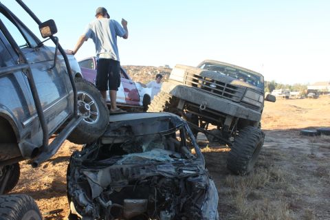 Mud-covered 1992 Ford truck on top of crushed car