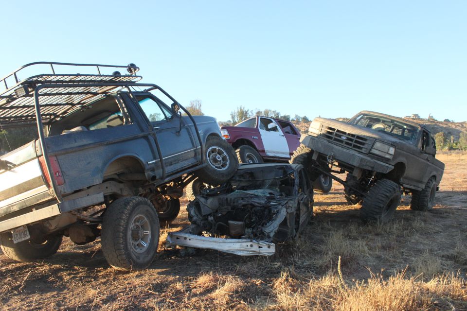 Three lifted trucks are stacked on top of each other in a field