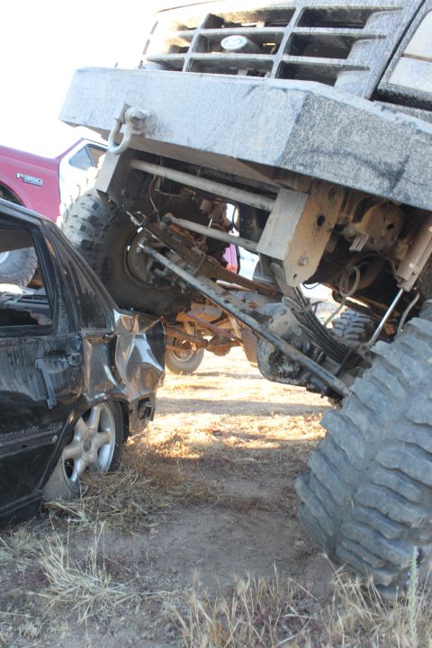 Large truck on top of a crushed car, both vehicles damaged