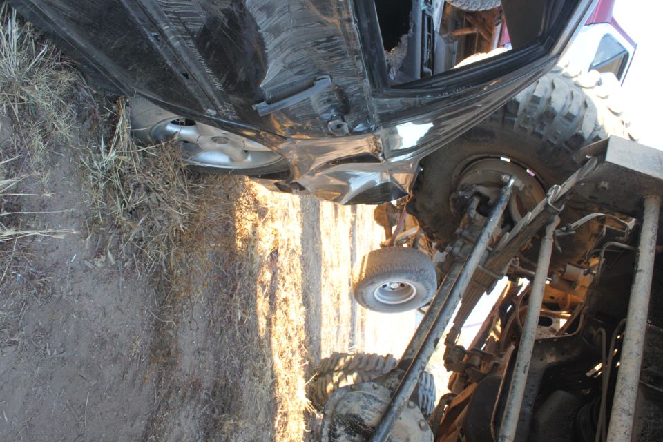vehicle on its side with visible damage to the body and suspension. Large off-road tires are prominent