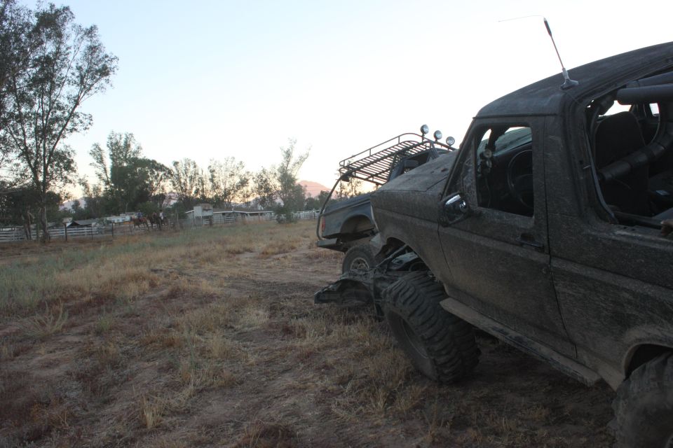 Mud-covered 1992 Ford Bronco with roof rack and off-road tires parked in a dry field