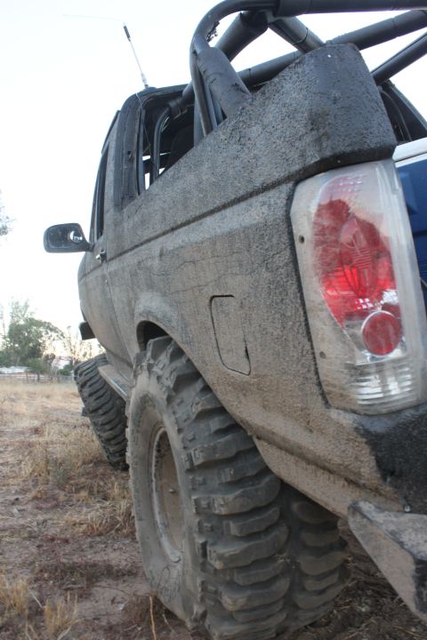 1992 Ford Bronco rear passenger side, covered in mud, with large off-road tires