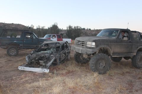 1992 Ford Bronco front 3/4 view, muddy, with another Bronco and wrecked car