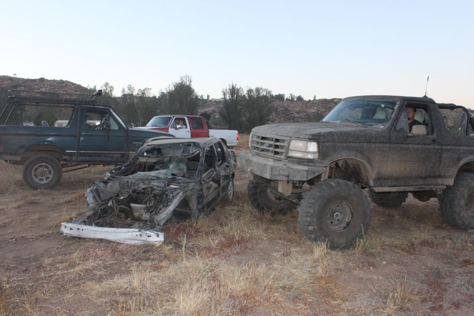 1992 Ford Bronco front 3/4 view, muddy, with another Bronco and wrecked car