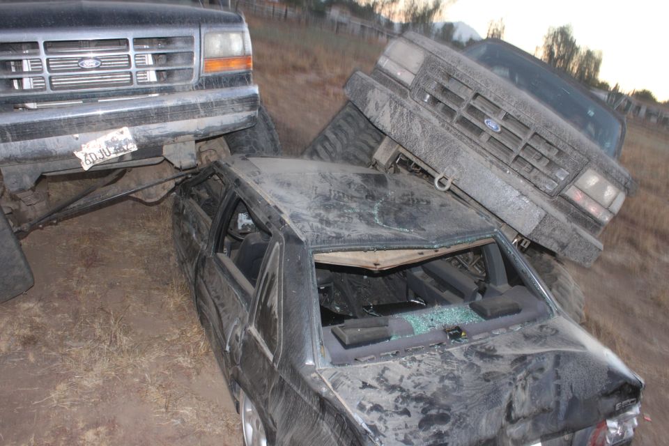 Two Ford trucks on top of a wrecked car. 1992 Ford Bronco