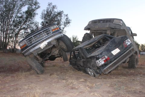 Ford Bronco on top of a crushed sedan, both vehicles are heavily damaged
