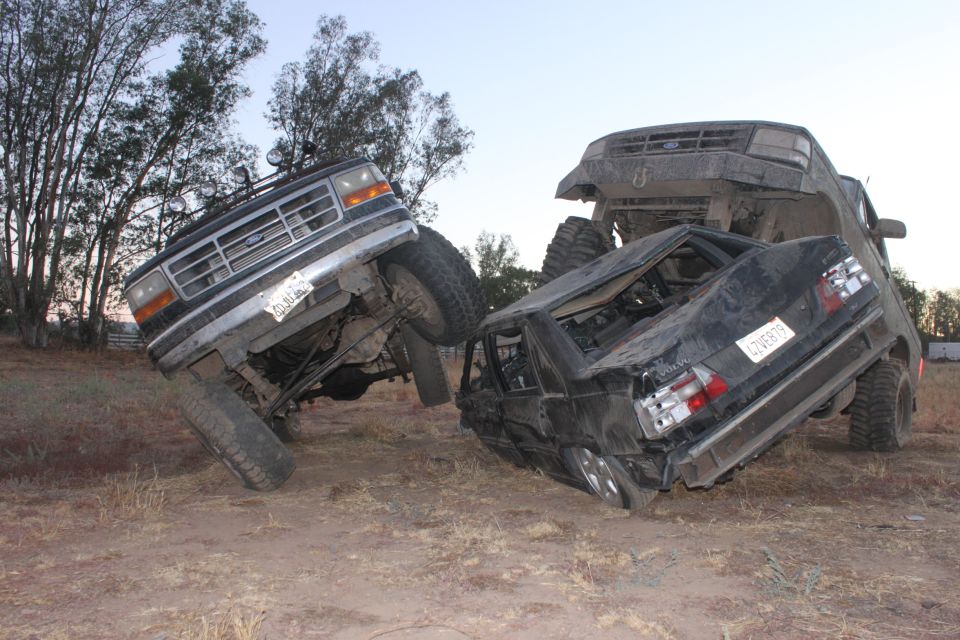 Ford Bronco on top of a crushed sedan, both vehicles are heavily damaged