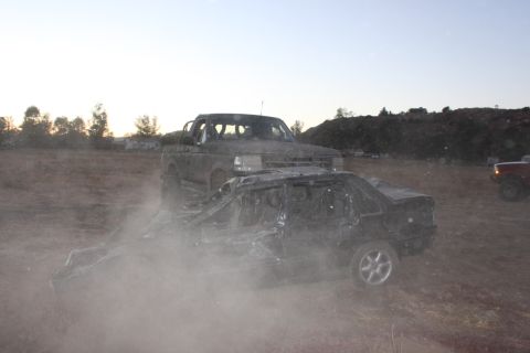 1992 Ford Bronco behind a crushed car in a dusty outdoor scene