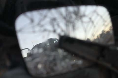 Reflection of dark SUV in side mirror, trees in background