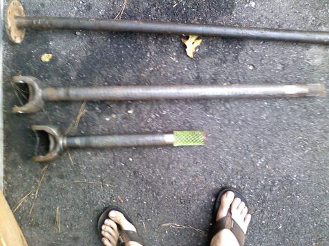 1990 Ford Bronco - Three drive shafts are shown on asphalt, with one having a distinct yellow-green splined end.