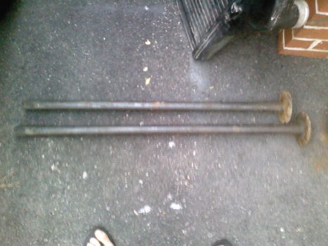 1990 Ford Bronco - Two metal shafts with flanges are shown lying on a concrete surface.