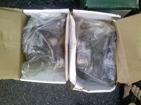 1990 Ford Bronco - Two boxes containing car parts, wrapped in plastic, sit on the ground.
