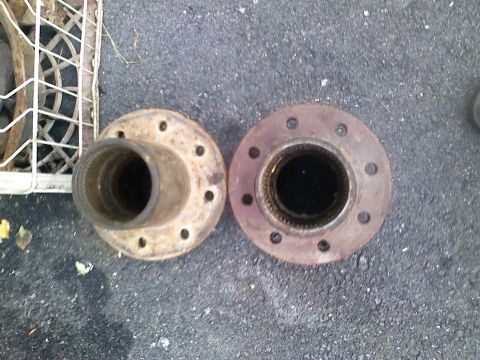 1990 Ford Bronco - Two rusty wheel hubs are shown side-by-side on a paved surface.