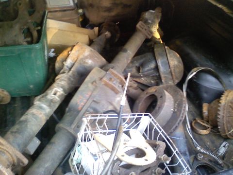 1990 Ford Bronco - A collection of used vehicle axles and brake components are stored together.