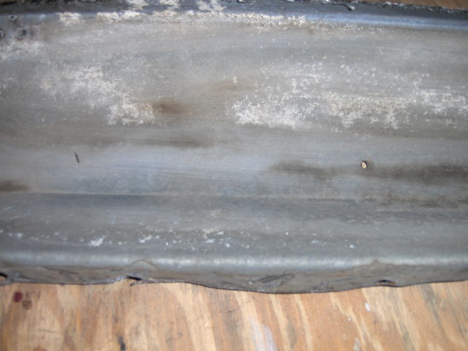 Weathered metal car part, possibly a bumper or trim piece