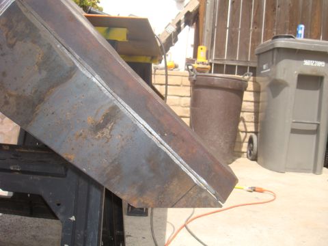 1992 Ford Bronco - A close-up view of a metal part undergoing fabrication, showing weld lines and surface rust.