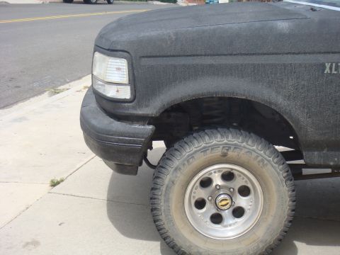 1992 Ford Bronco - A close-up view of the front fender and wheel of a black Ford F-Series truck, possibly an F-150 or F-250.