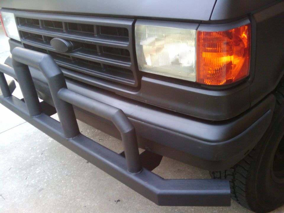 Front corner of dark Ford truck with black tubular brush guard and amber corner lamp