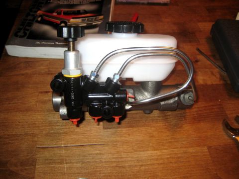 1996 Ford Bronco - A brake master cylinder assembly with a white reservoir and black components is shown on a wooden surface.