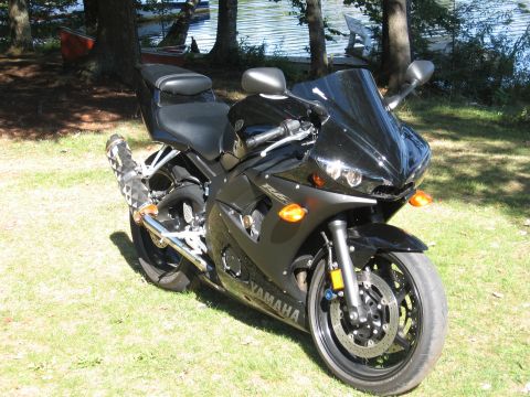 2008 Yamaha R1 - A black Yamaha motorcycle is parked on a grassy area next to a body of water with trees in the background.