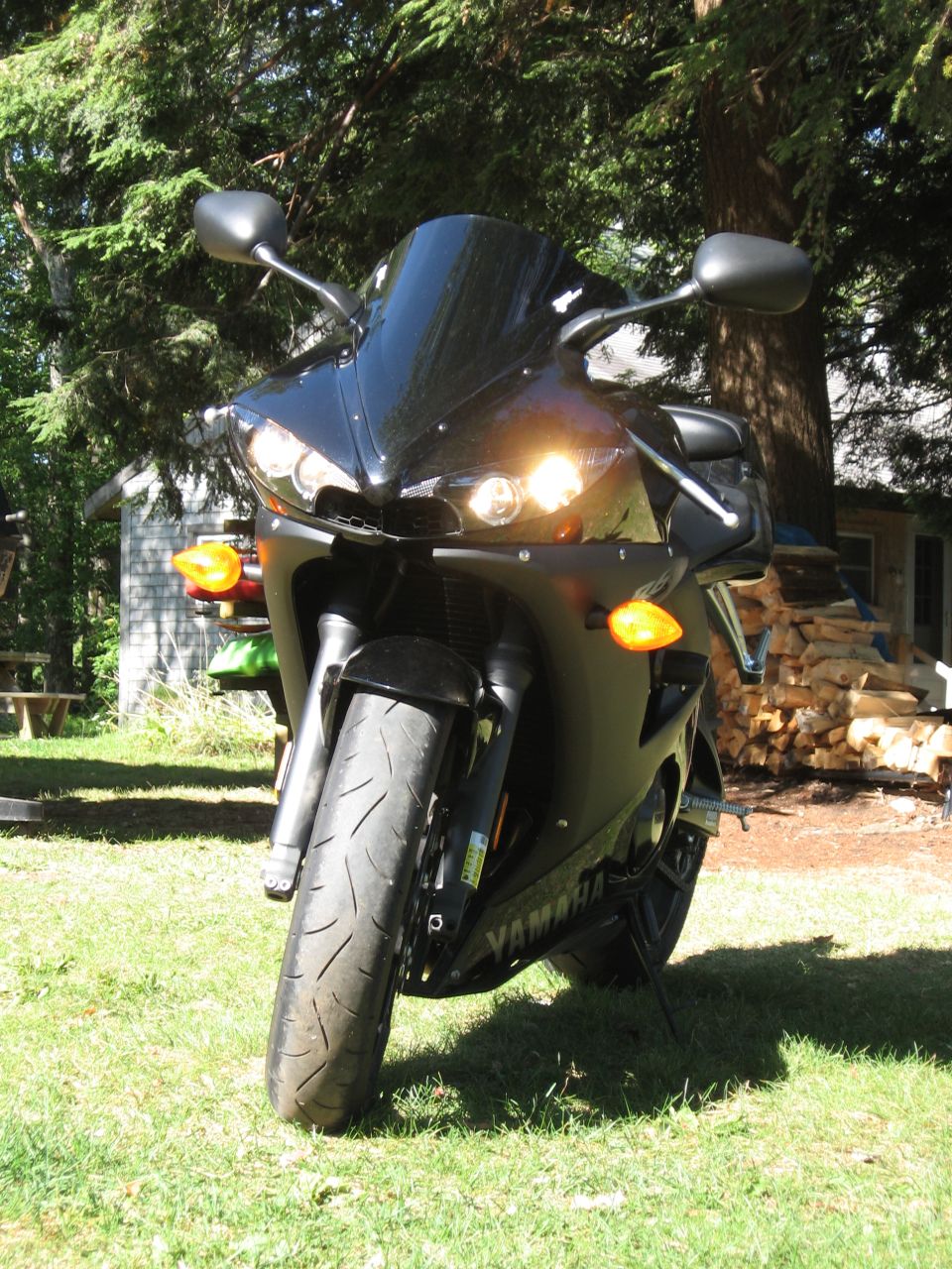 Black Yamaha motorcycle parked on grass, front view, with headlights on