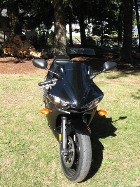 2008 Yamaha R1 - A black motorcycle is parked on a grassy area with trees in the background.