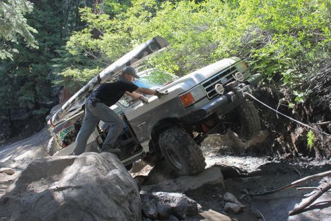 1991 Ford Bronco - A man attempts to maneuver a lifted Ford Bronco over a difficult rocky trail.