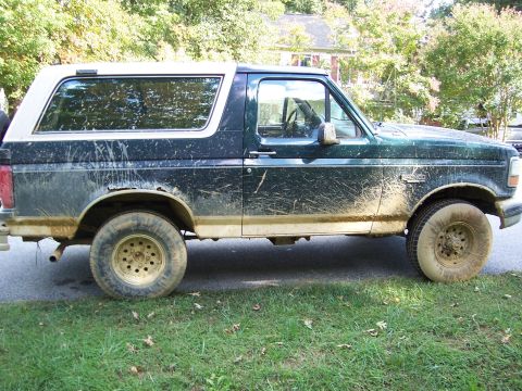 1992 Ford Bronco - Muddy 1992 Ford Bronco parked on grass.