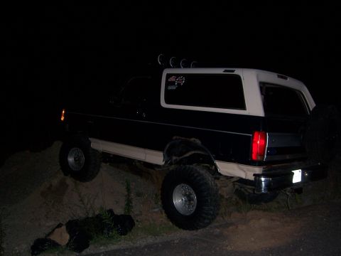 1992 Ford Bronco - This lifted Ford Bronco is shown off-roading on a dirt incline in the dark.