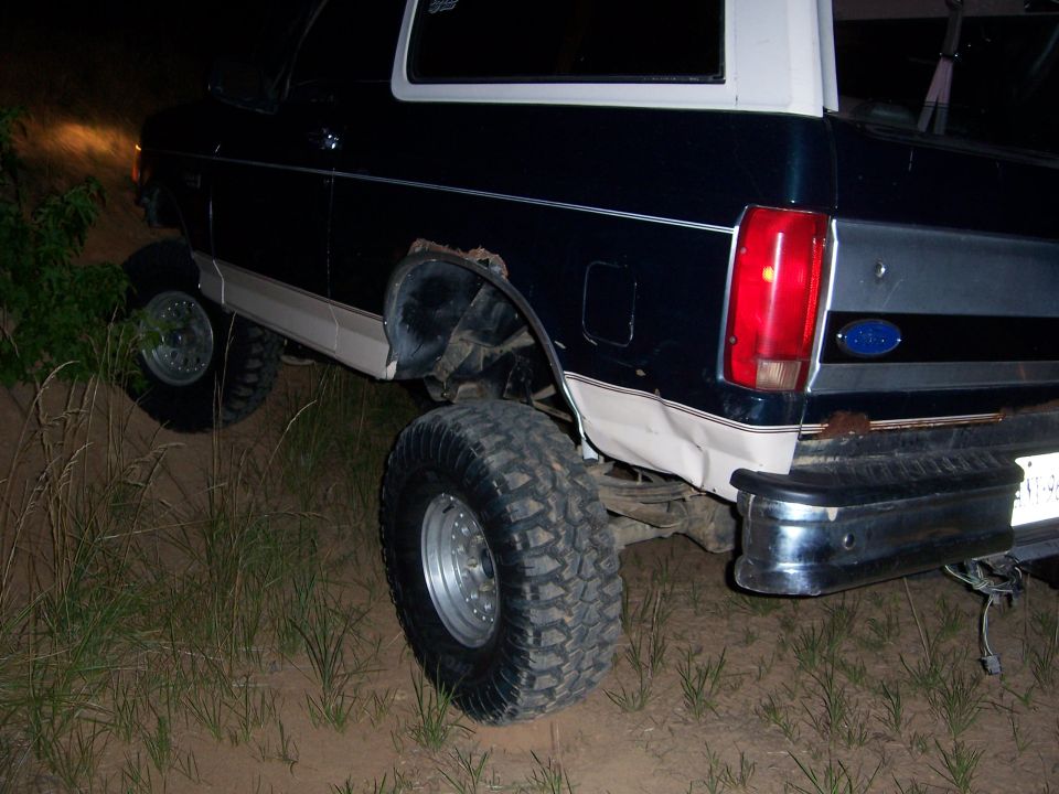 Dark green and white Ford Bronco with off-road tires on uneven terrain