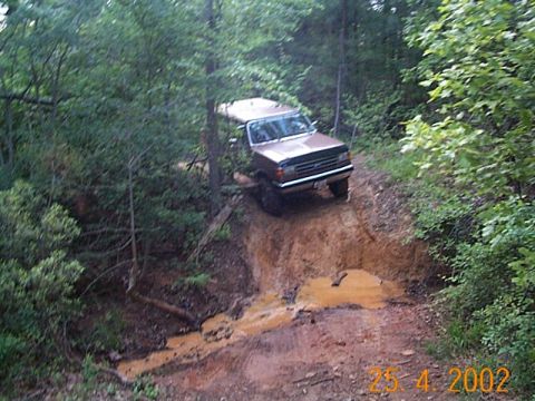 1986 Ford Bronco - This 1986 Ford Bronco navigates a challenging off-road path through a wooded area.