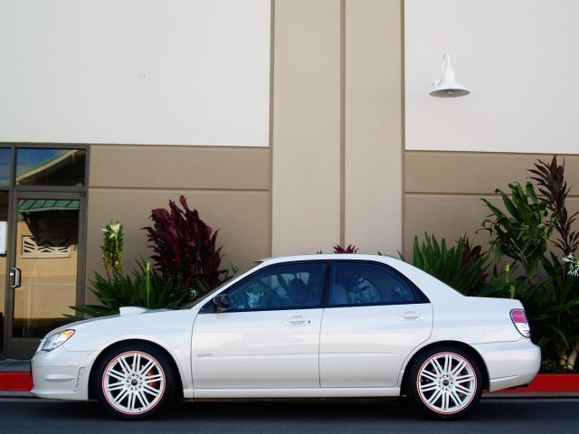 White sedan side view with red trim on wheels