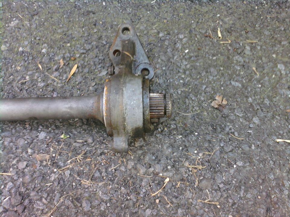 Driveshaft part with splines and mounting bracket on asphalt