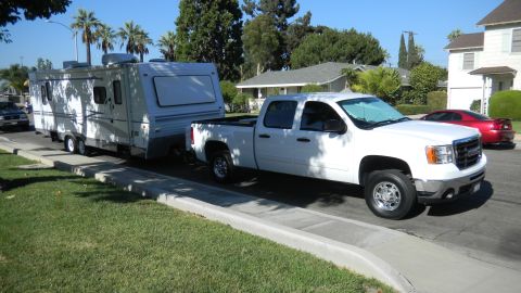 1997 Ford Ranger - White GMC Sierra pickup truck towing a travel trailer on a sunny day.