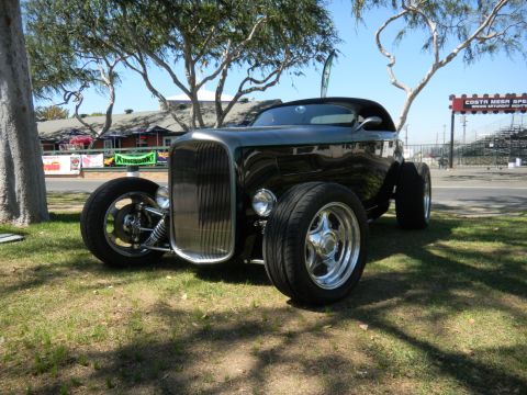 1997 Ford Ranger - A classic hot rod is displayed outdoors with trees and bleachers in the background.