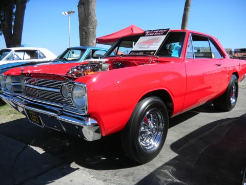 1997 Ford Ranger - A bright red 1967 Dodge Dart Super Stock is displayed at a car show with its hood up, revealing the engine.