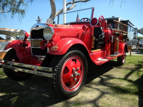 1997 Ford Ranger - A vintage red fire truck from 1928 is parked on grass under a tree.