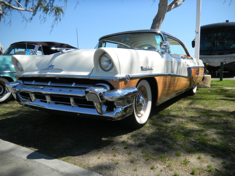 1955 Mercury Montclair, white and wood-paneled, 3q-front view. Another car is partially visible to the left
