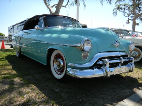 1997 Ford Ranger - A teal 1950s Oldsmobile convertible is parked outdoors next to another vehicle.