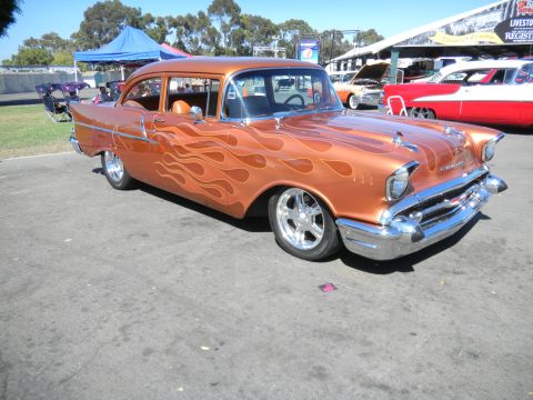 1997 Ford Ranger - A classic orange 1957 Chevrolet Bel Air with flame graphics is displayed at an outdoor event.