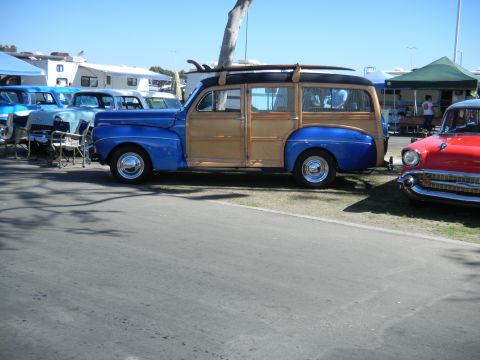 1997 Ford Ranger - A vintage woodie station wagon with surfboards on its roof is parked at an outdoor event.