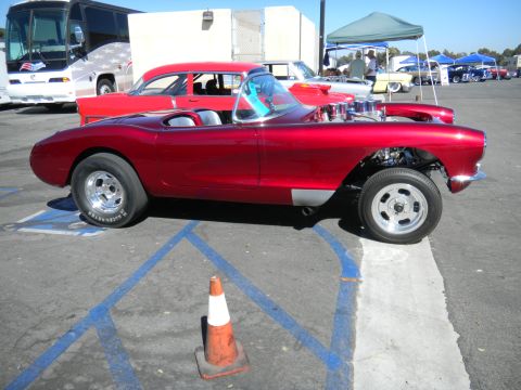 1997 Ford Ranger - A custom red convertible with a powerful engine is displayed at a car show, alongside other vehicles and tents.