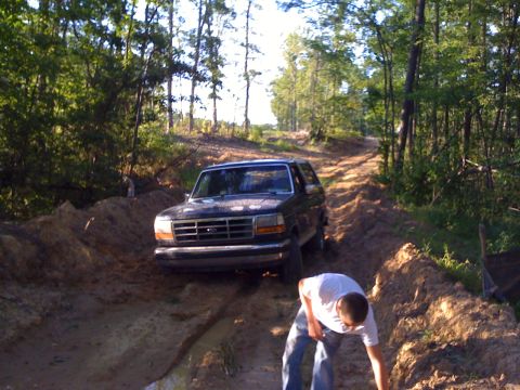 1992 Ford Bronco - Ford Bronco navigates a challenging off-road course through a wooded area.