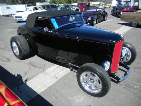 1997 Ford Ranger - A black hot rod convertible with a prominent red grille and wide rear tires is parked at an outdoor event.
