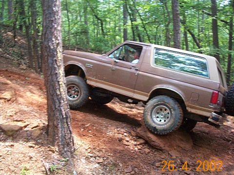 1986 Ford Bronco - Brown Ford Bronco navigates a challenging off-road course with significant elevation changes.