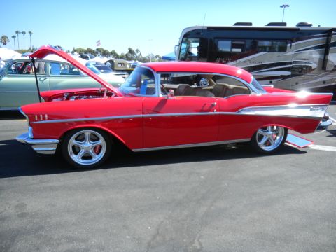 1997 Ford Ranger - A bright red 1957 Chevrolet Bel Air convertible is displayed with its hood open at a car show, with other vehicles visible in the backgroun…