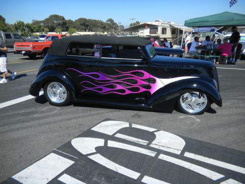 1997 Ford Ranger - A custom hot rod with flame decals is displayed at an outdoor gathering with other vehicles and people.