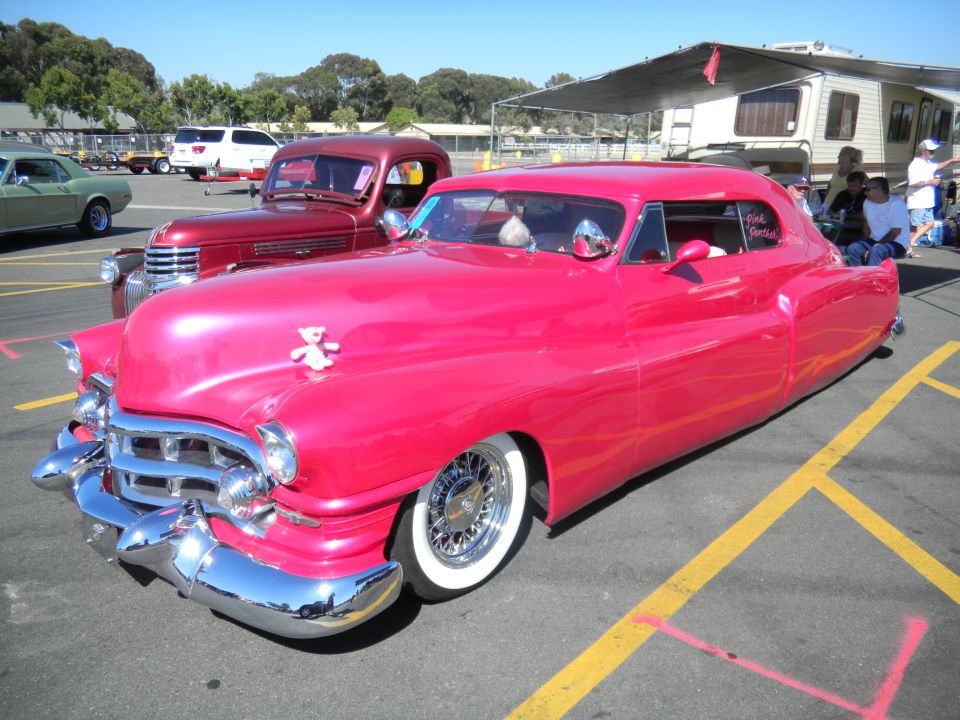 Pink custom car with chrome grille and whitewall tires