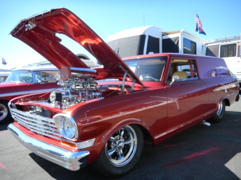 1997 Ford Ranger - A customized red panel van with an exposed supercharged engine is displayed at a car show next to another vintage vehicle.